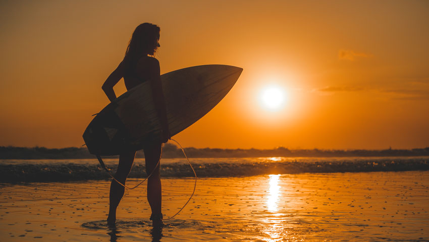 girl posing with a board at sunset