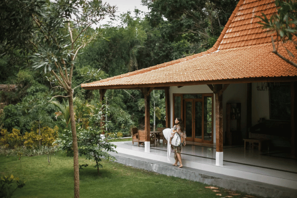 Girl walking with surfboard next to suite Bali